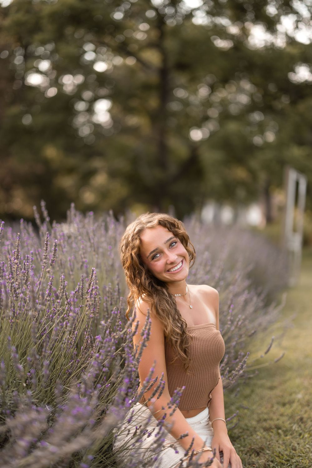 A person sits among blooming purple lavender flowers in a garden on a sunny summer day.