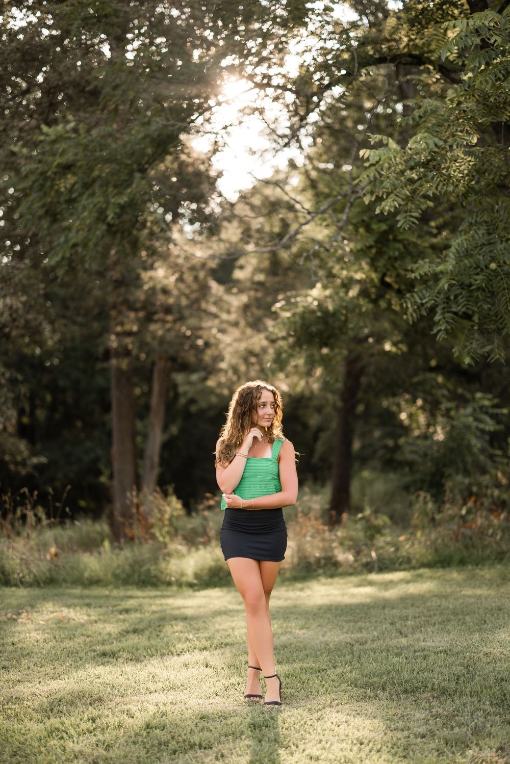 A scenic summer portrait taken in a lush garden setting with golden sunlight filtering through trees.