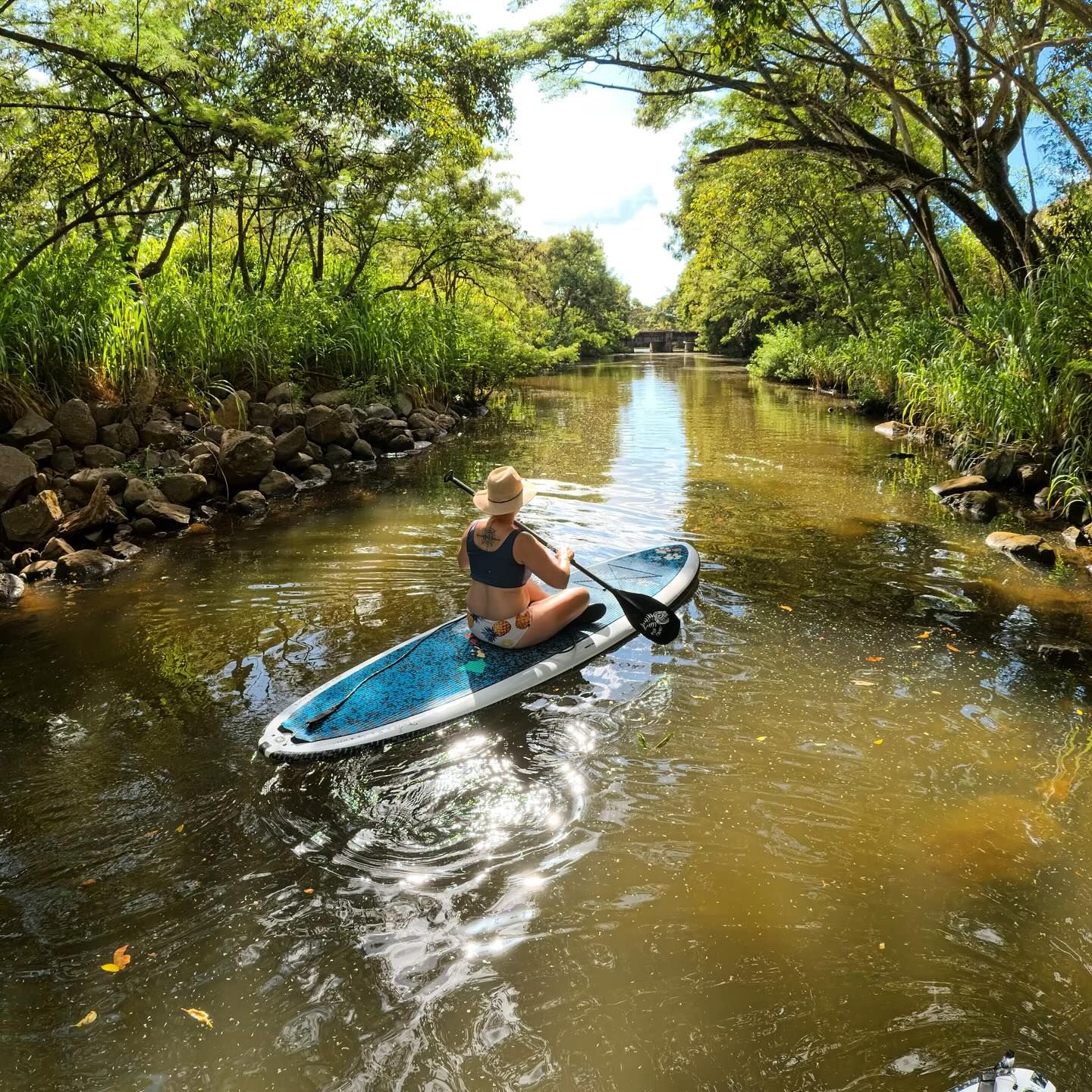 Maggie adventuring in Hawaii, paddle boarding down a river.