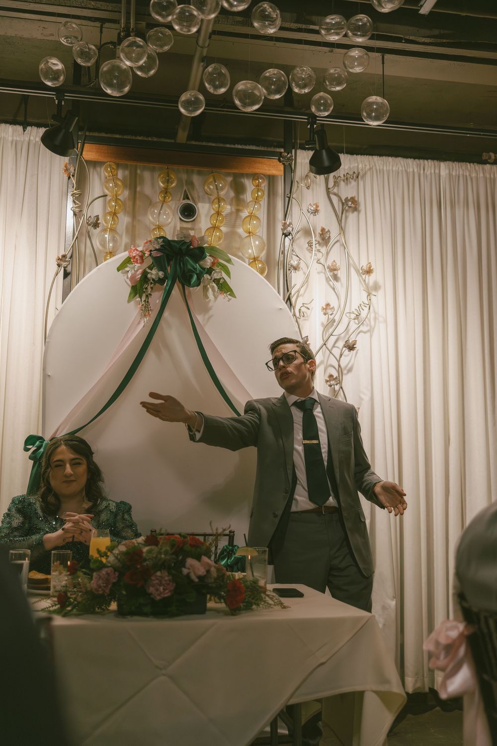Elegant wedding reception setup with floating glass bubbles and floral decorations under soft lighting.