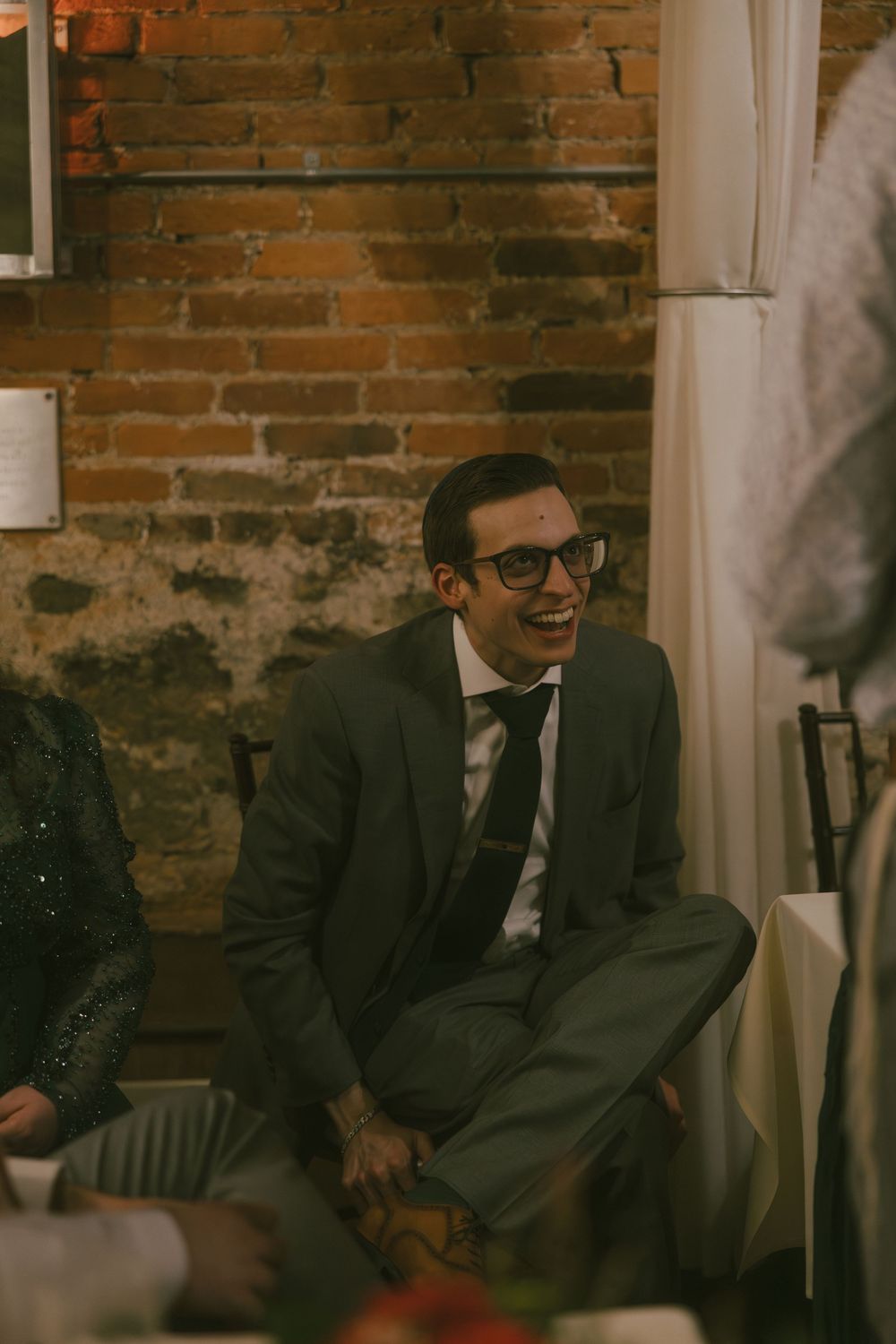 Guests sharing genuine laughter at an indoor venue with exposed brick walls.
