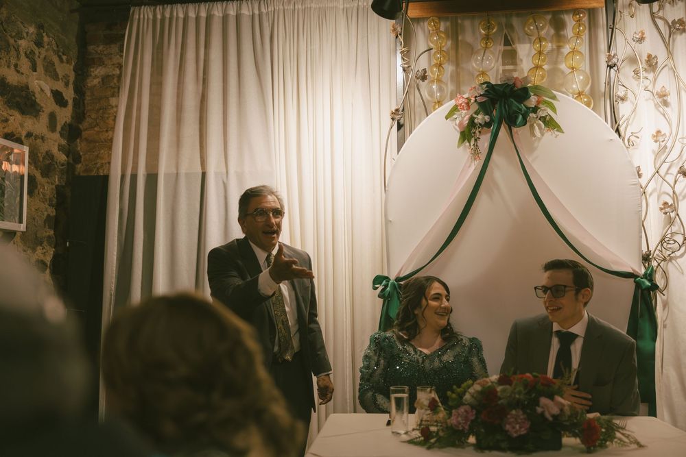 Wedding celebration in an intimate venue with decorative white backdrop and mood lighting.