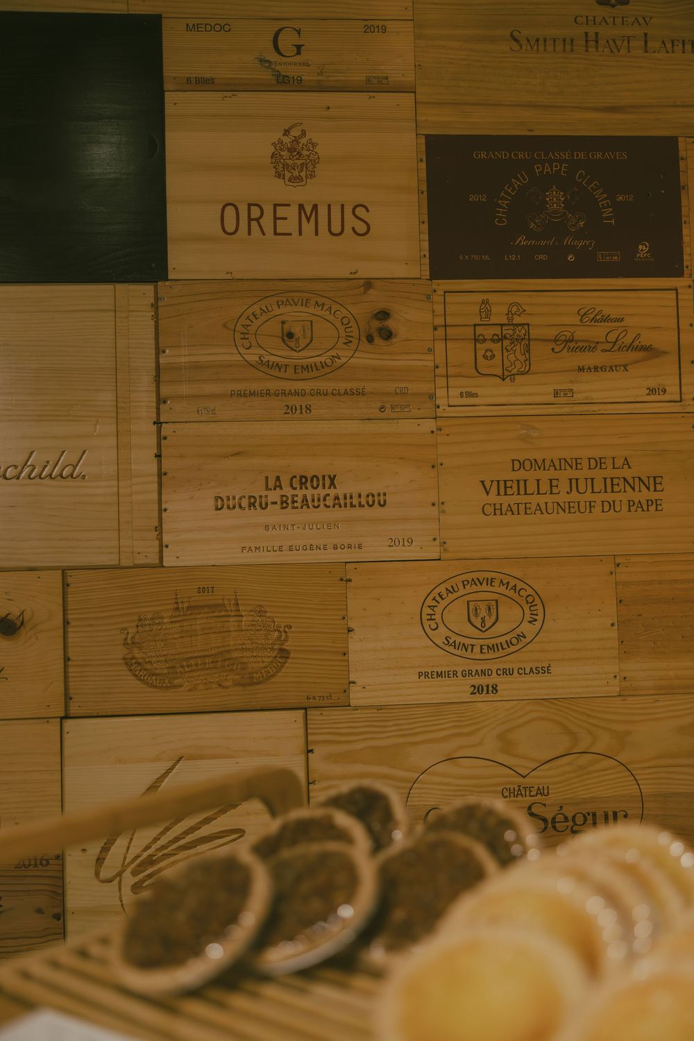 Collection of vintage wine crates and wooden boxes with French vineyard labels stacked together.