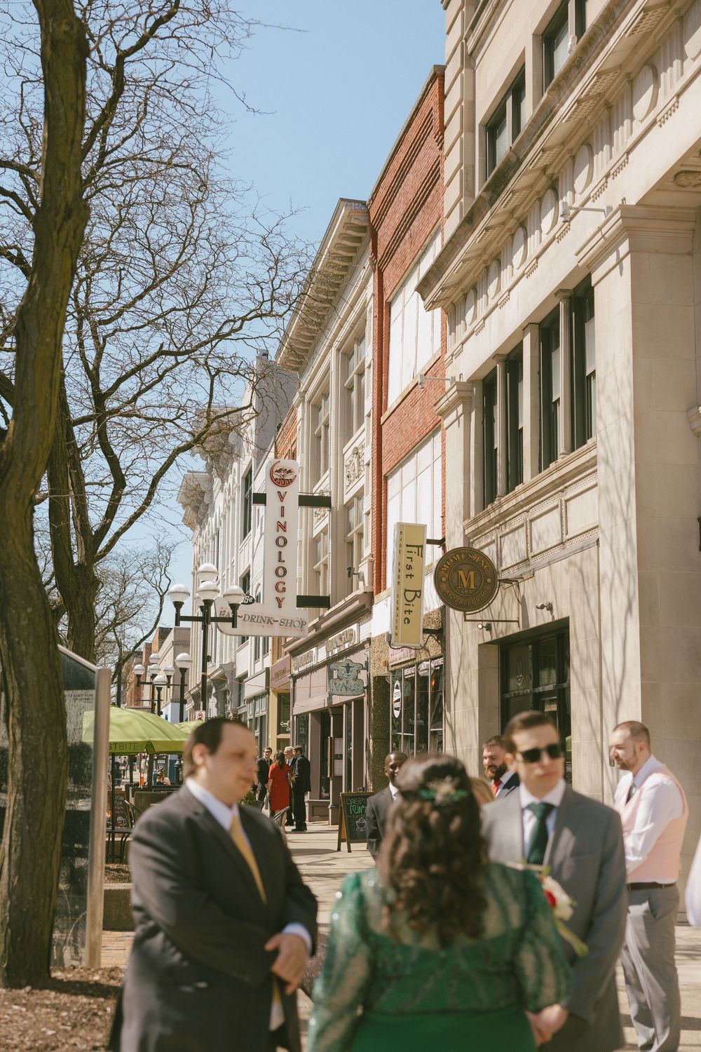 A small group gathered on a historic downtown street with classic storefronts and architecture.