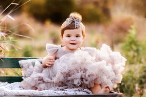 A series of connected photos showing a baby in a white tutu dress playing outdoors in soft natural lighting.