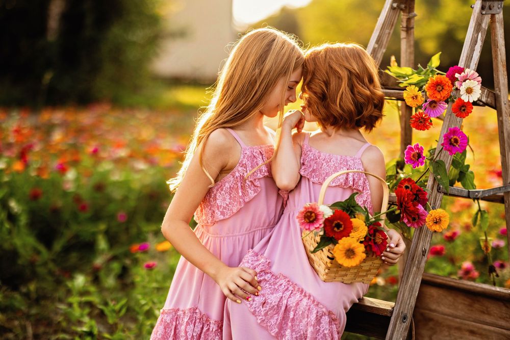 Young girl in a pink dress walks through a vibrant flower garden with colorful blooms on a sunny day.