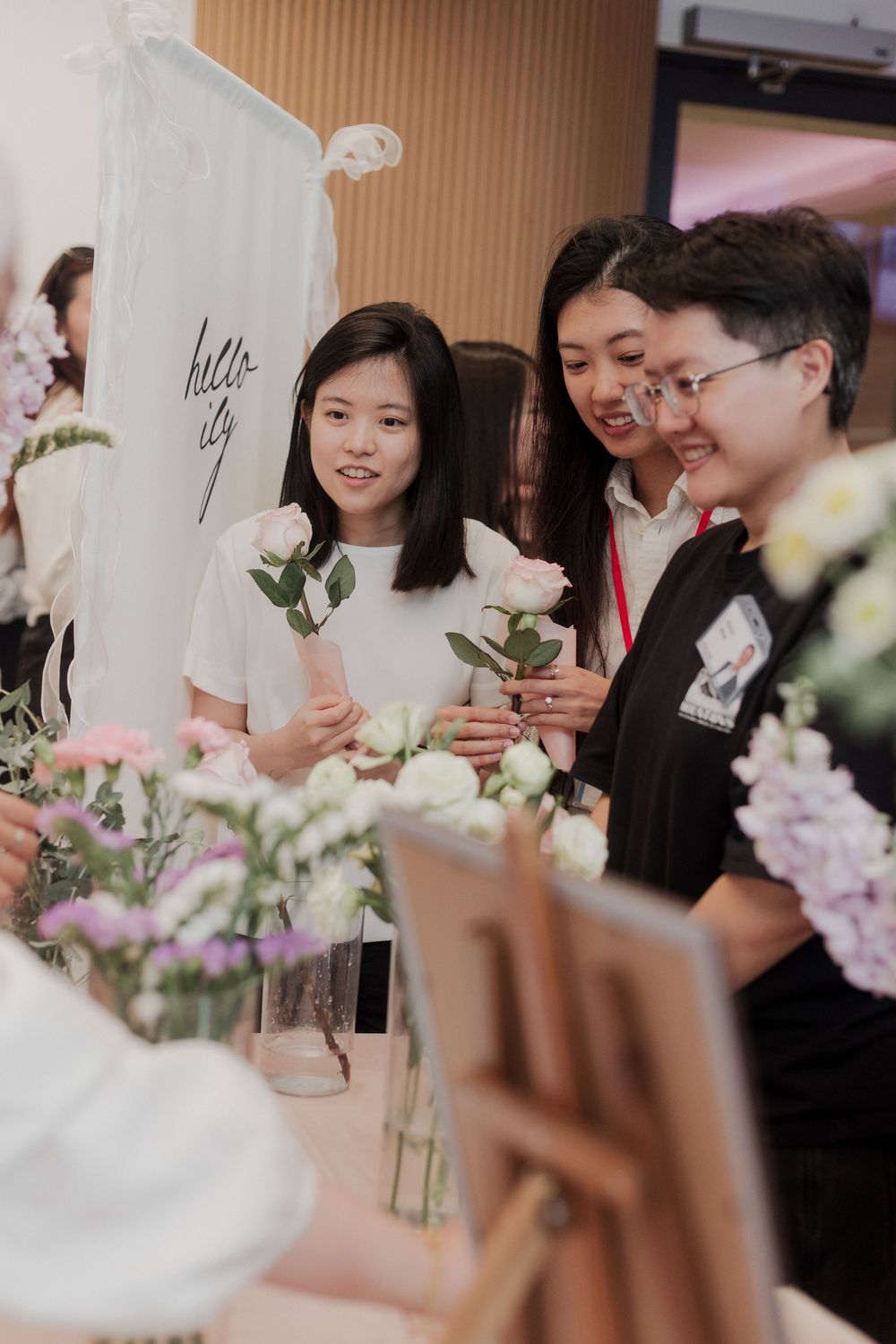 Workshop participants gather around a table with elegant white and purple floral arrangements.