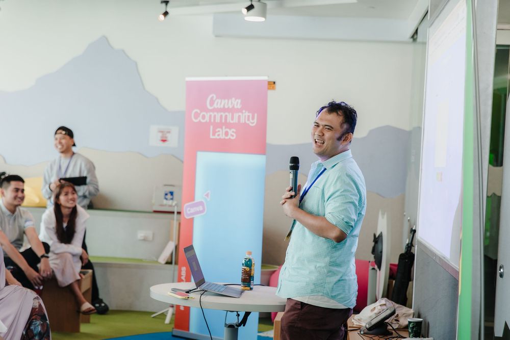 Speaker presenting at a Canva community event in a modern office space.