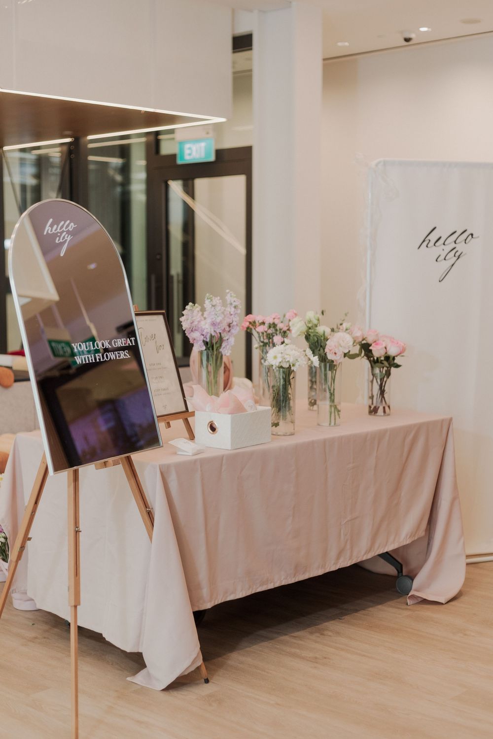 Elegant table setup with floral arrangements and digital display on easel.