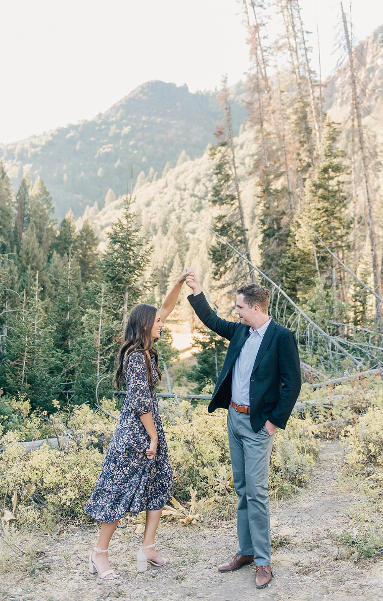 Couple dancing together on mountain trail during golden hour.