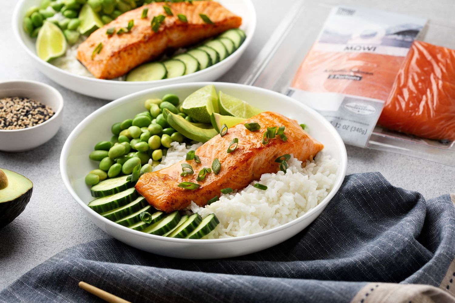 Salmon rice bowl with avocado, edamame, cucumber, and white rice, served with a packaged salmon fillet nearby.