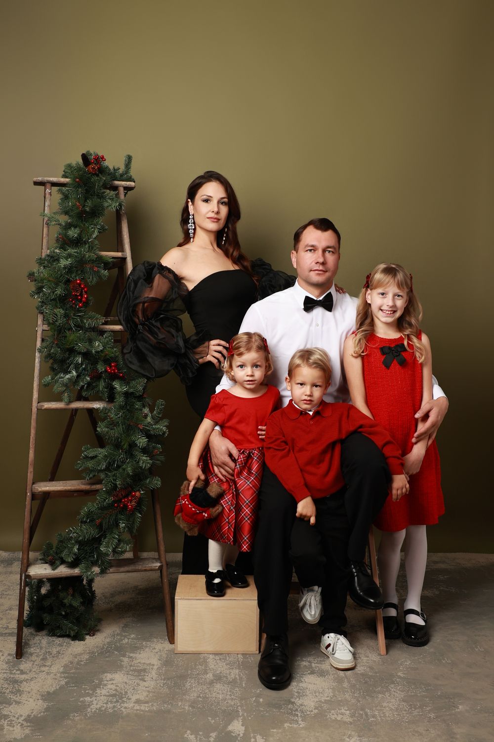 A creative photo series showing a family in formal attire sitting on boxes with a Christmas tree in progressive frames.