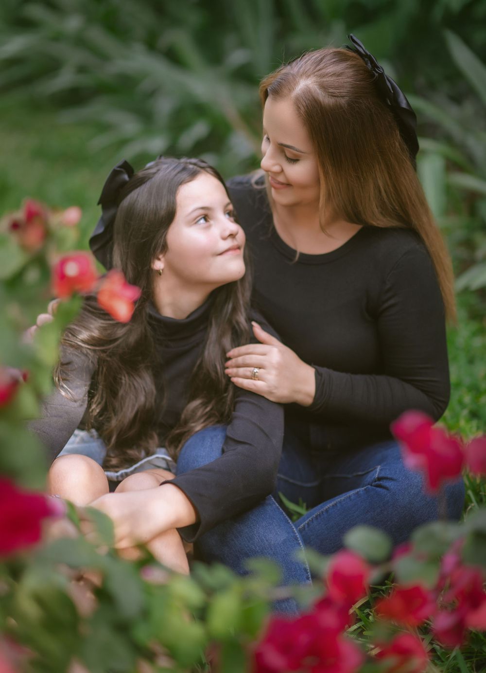 A tender moment between two people sitting among vibrant red flowers in a garden setting.