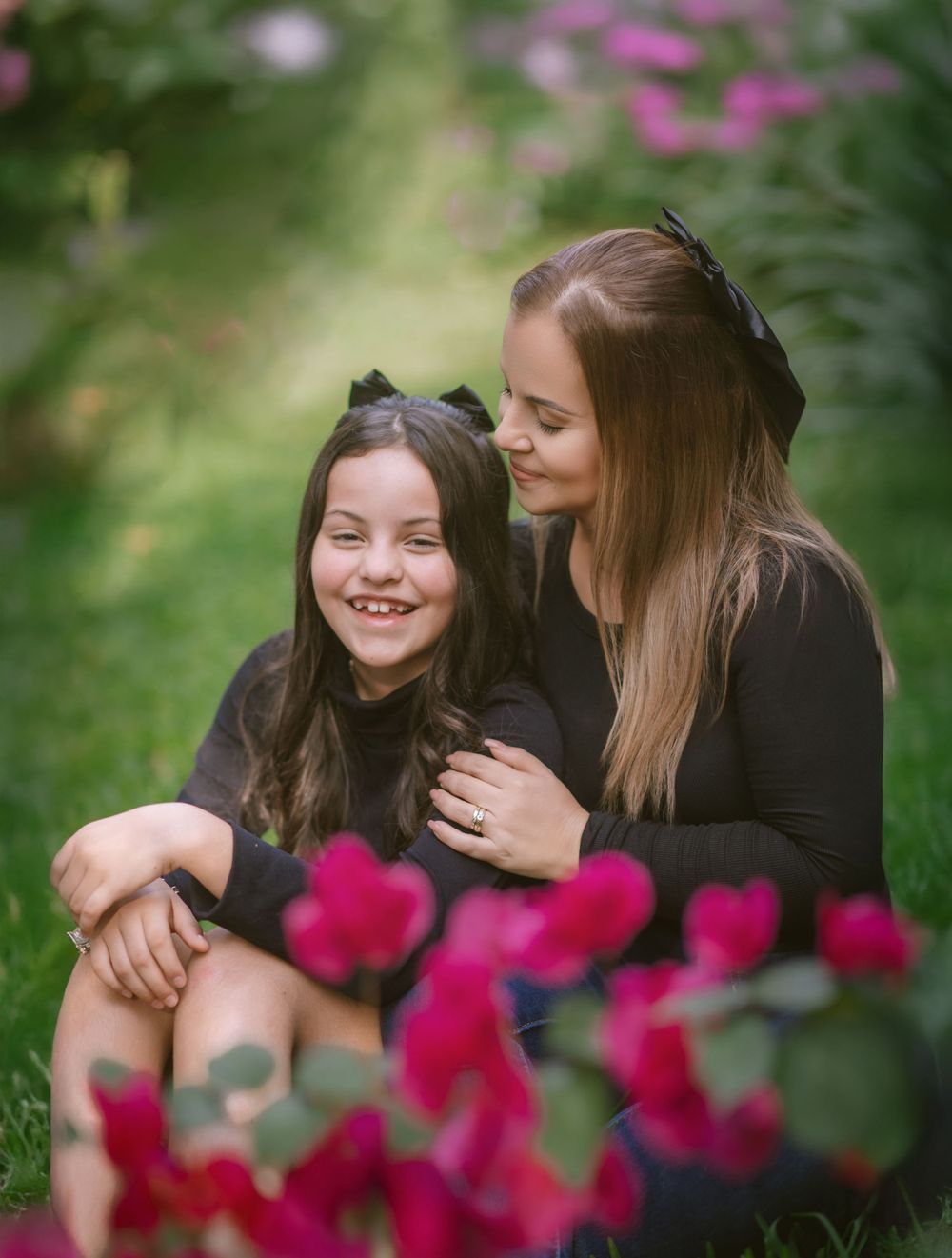 Two people sharing a joyful moment together outdoors with vibrant pink flowers in the foreground.