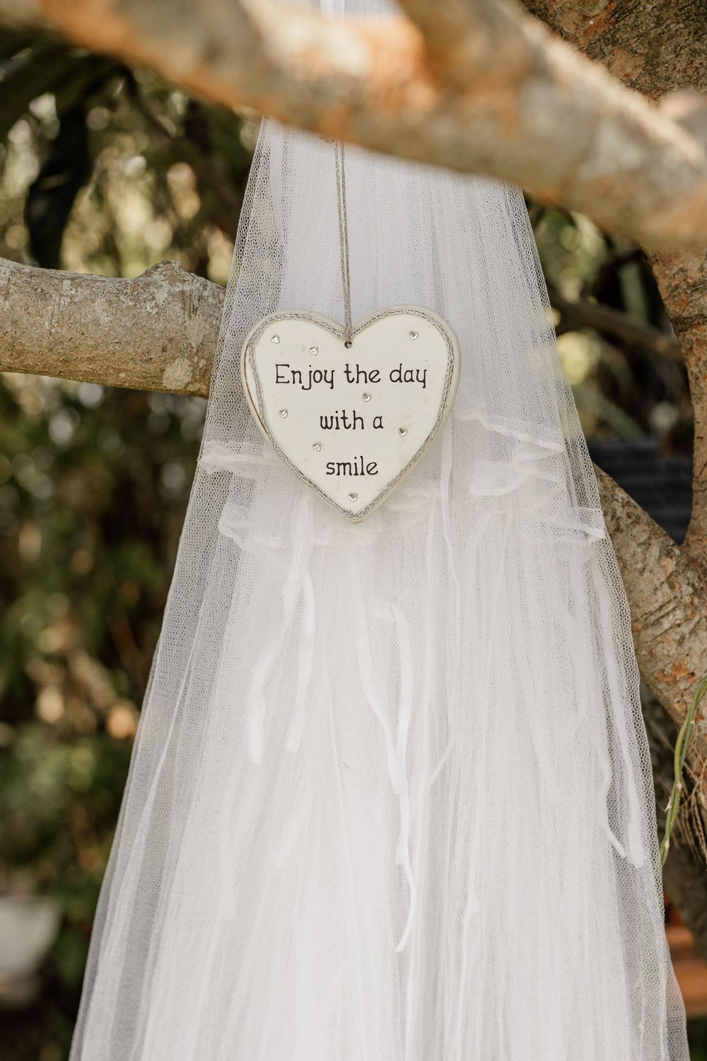 White heart decoration with inspirational message hanging on wedding veil.