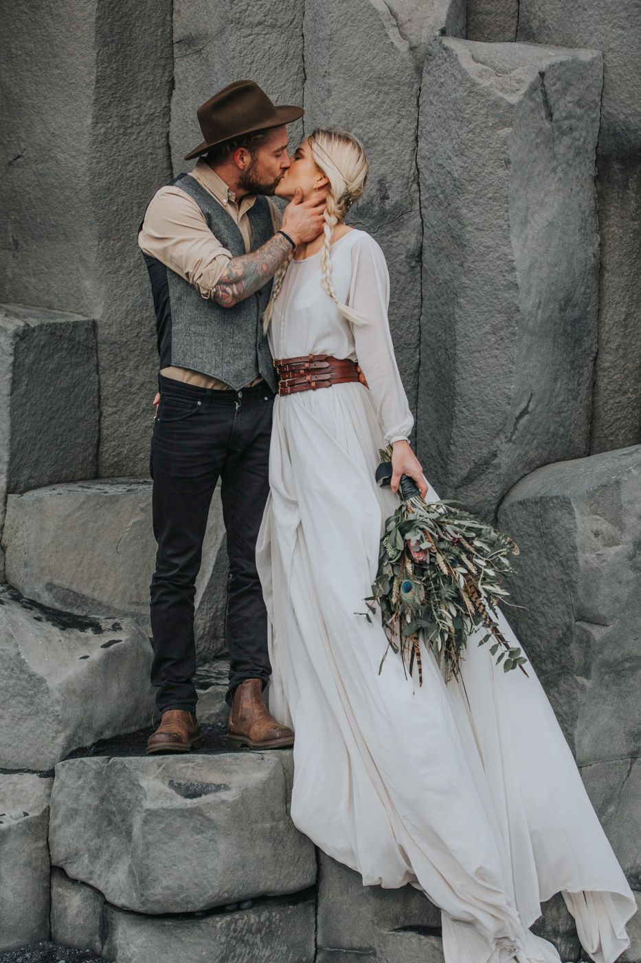 A tender moment captured between newlyweds on grey stone steps with a rustic bouquet.
