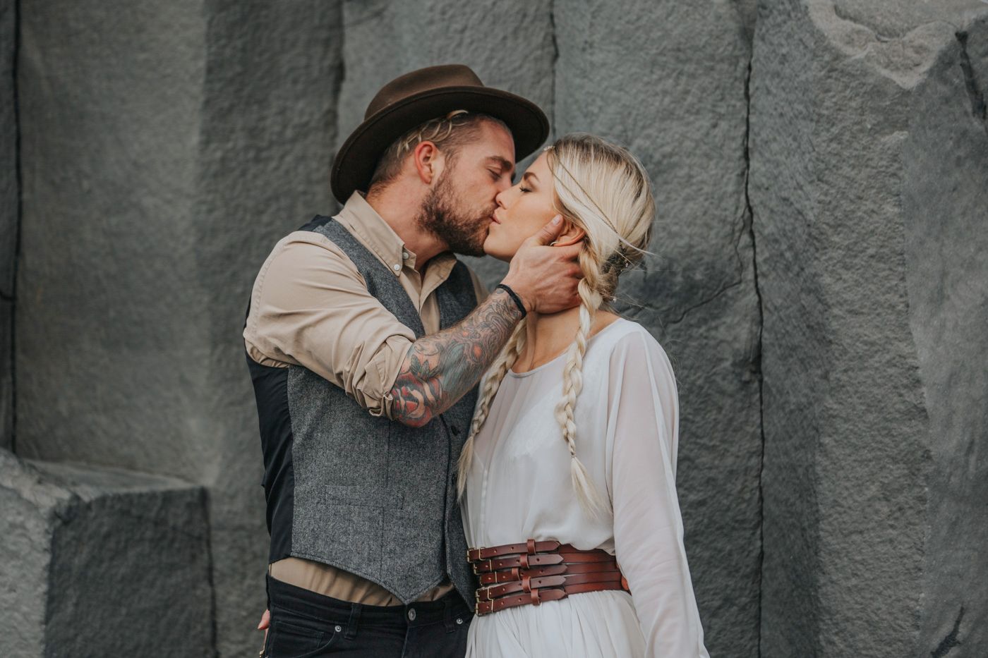An intimate wedding moment captured against textured grey stone walls.