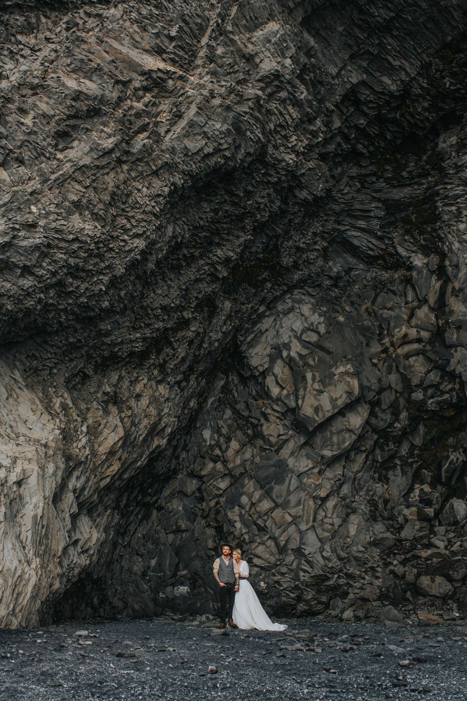 Dramatic aerial perspective of wedding couple dwarfed by towering rock formations.