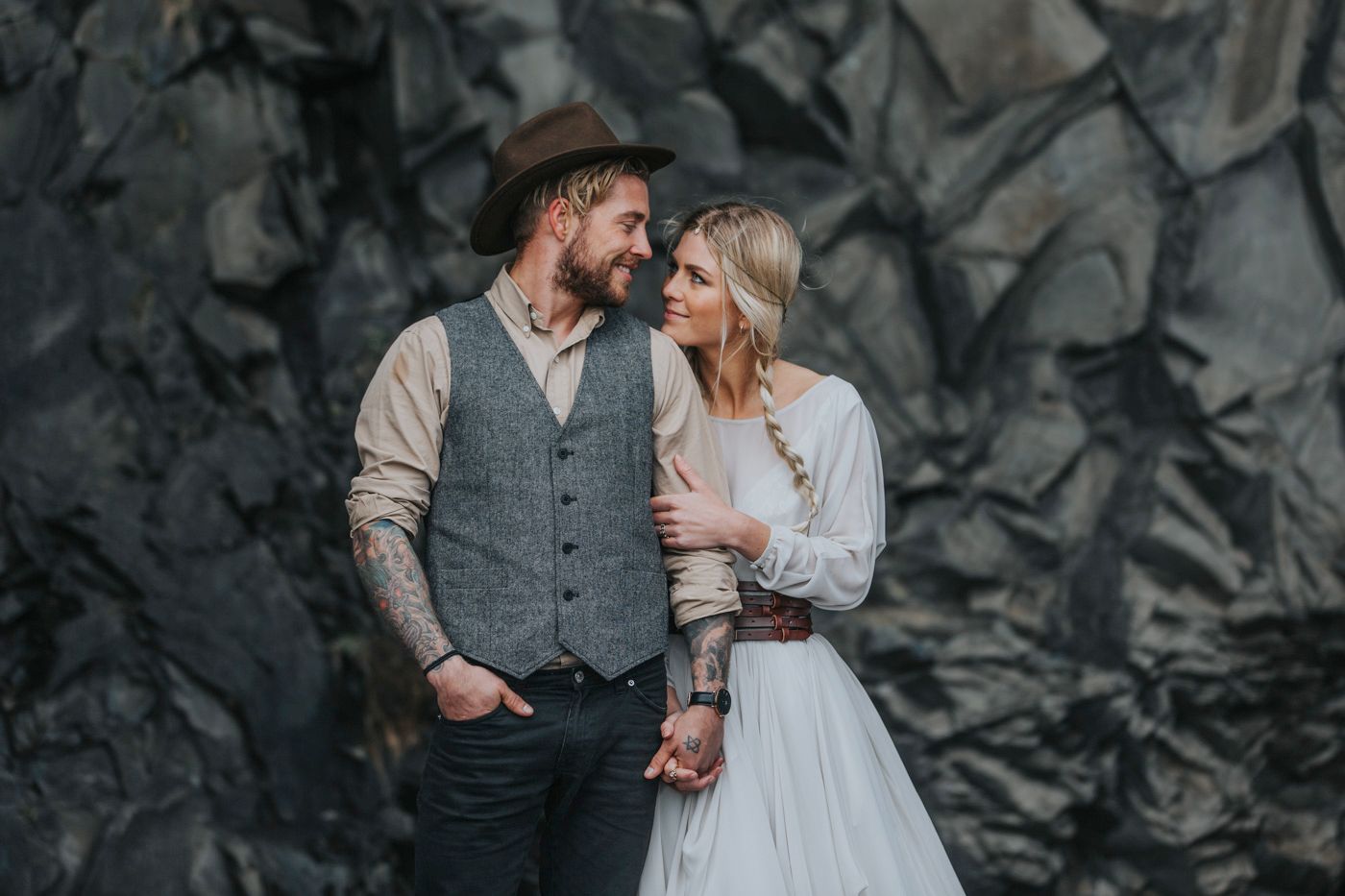 Intimate wedding portrait showing vintage-inspired style against moody rock backdrop.