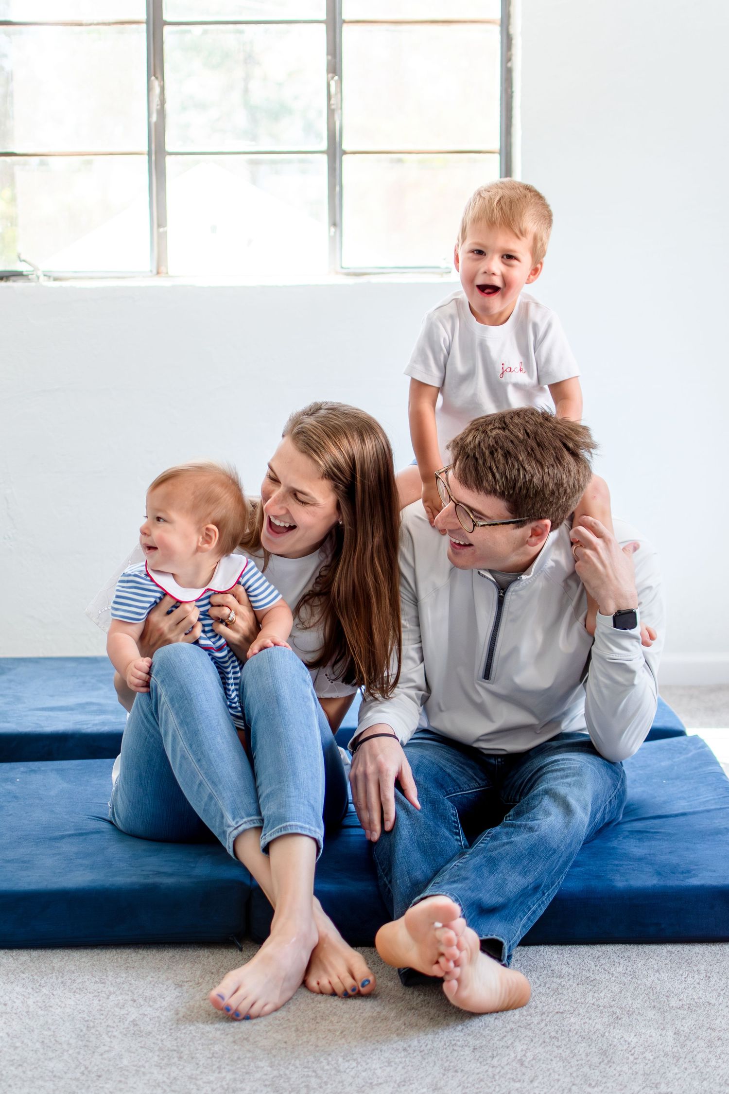 Two young boys smile as they are surrounded by mom and dad in the basement.