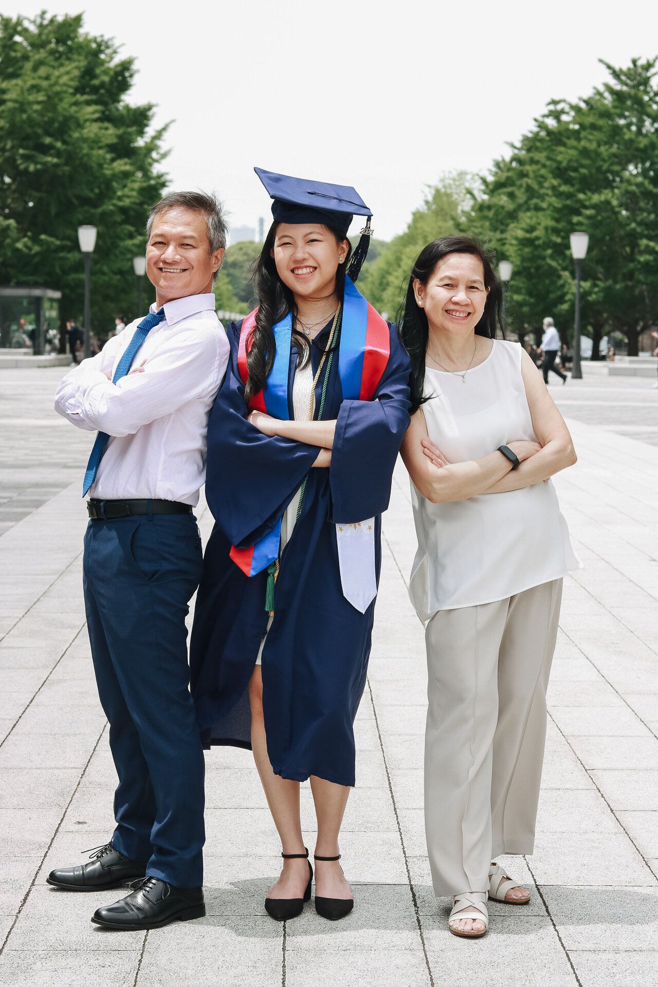 Family graduation portrait on plaza in front of historic building with trees in background.