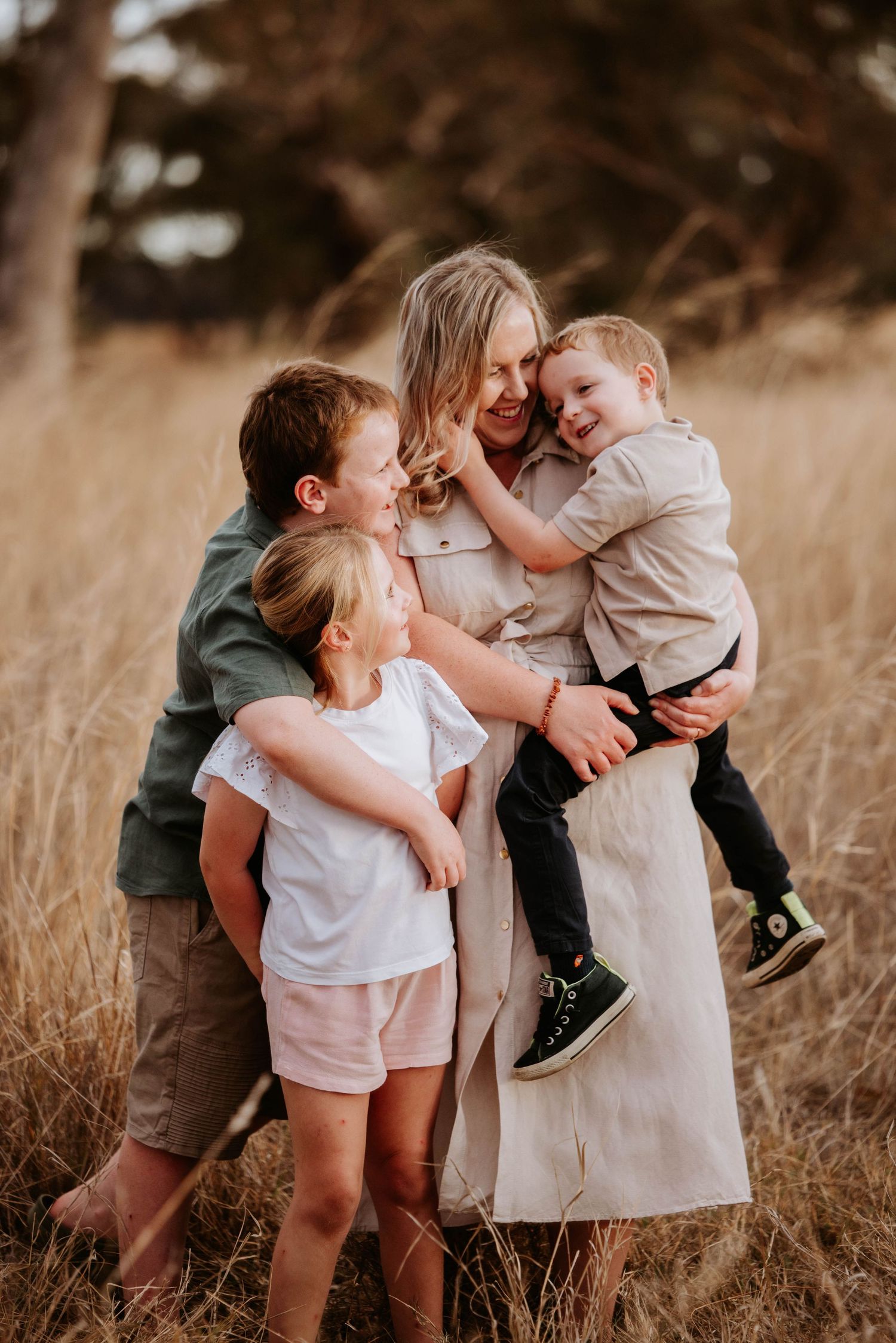 Candid family moment captured in tall grass during golden hour.