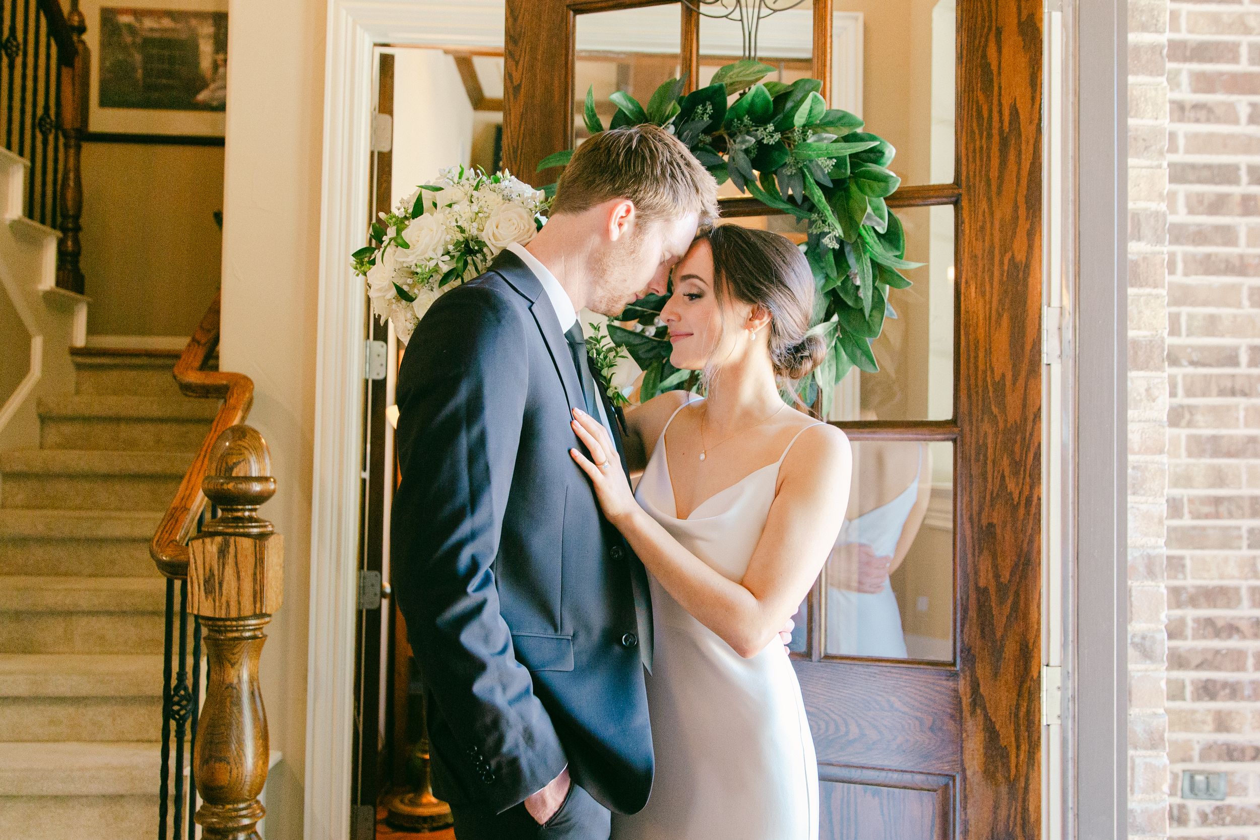 Romantic wedding scene in a sunlit room with white floral arrangements.