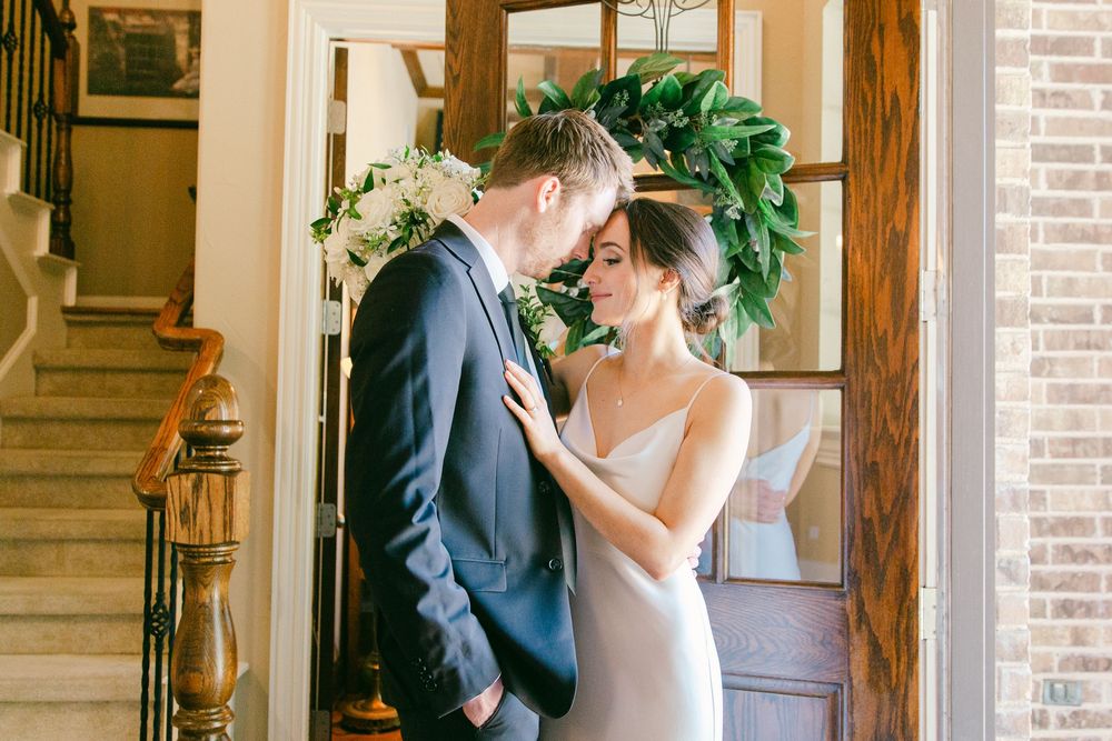 Romantic wedding scene in a sunlit room with white floral arrangements.