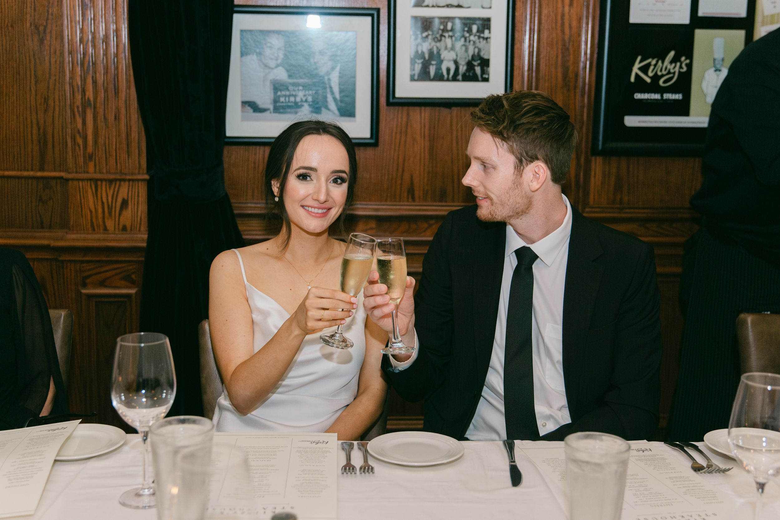 Couple toasting with champagne glasses at wedding reception dinner.