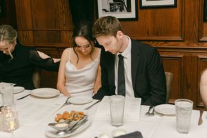 Wedding reception dinner at an elegant wood-paneled restaurant with vintage photos on walls.