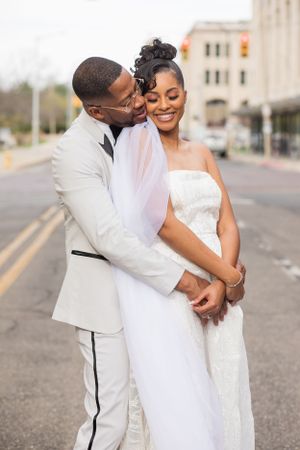 A joyful wedding moment captured on an urban street with elegant white attire.
