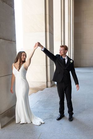 A bride in white gown and groom in black suit pose playfully together in a series of candid moments under columns.