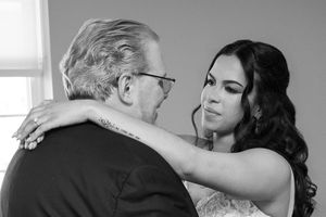 A black and white photo shows a tender dance moment between two people in formal attire at a celebration.