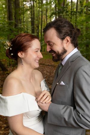 Romantic woodland wedding portrait of couple sharing intimate moment in formal attire.