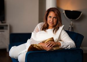 A person in a white sweater relaxes comfortably on a navy blue couch in a warmly lit living room.