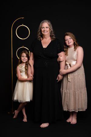 A photo series shows tender moments between two people in dark elegant dresses against a black backdrop.