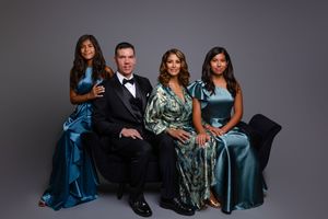 Professional group portrait photoshoot showing elegant poses against gray backdrop in formal evening attire.