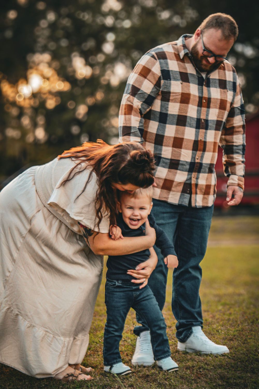 A playful family moment captured outdoors with warm sunset lighting and natural expressions.