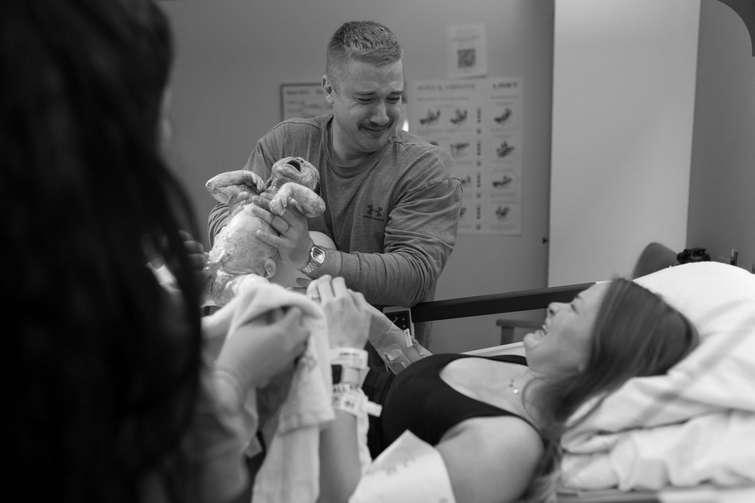 A tender moment between parent and newborn baby captured in black and white.