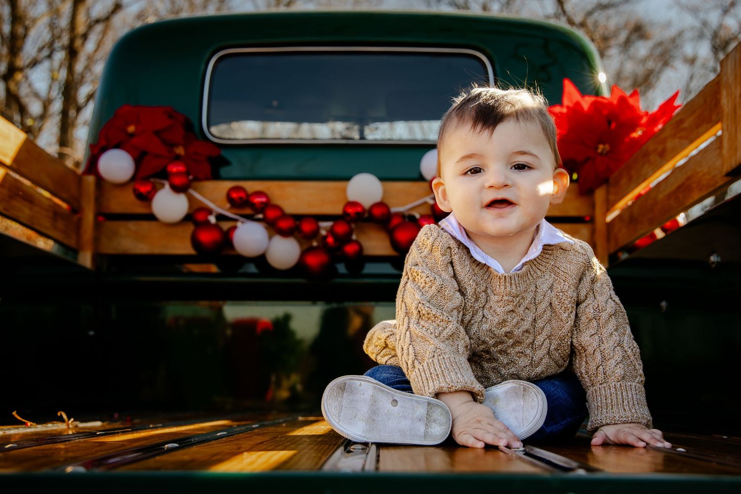 Children posing by vintage truck decorated with Christmas ornaments and festive decor.