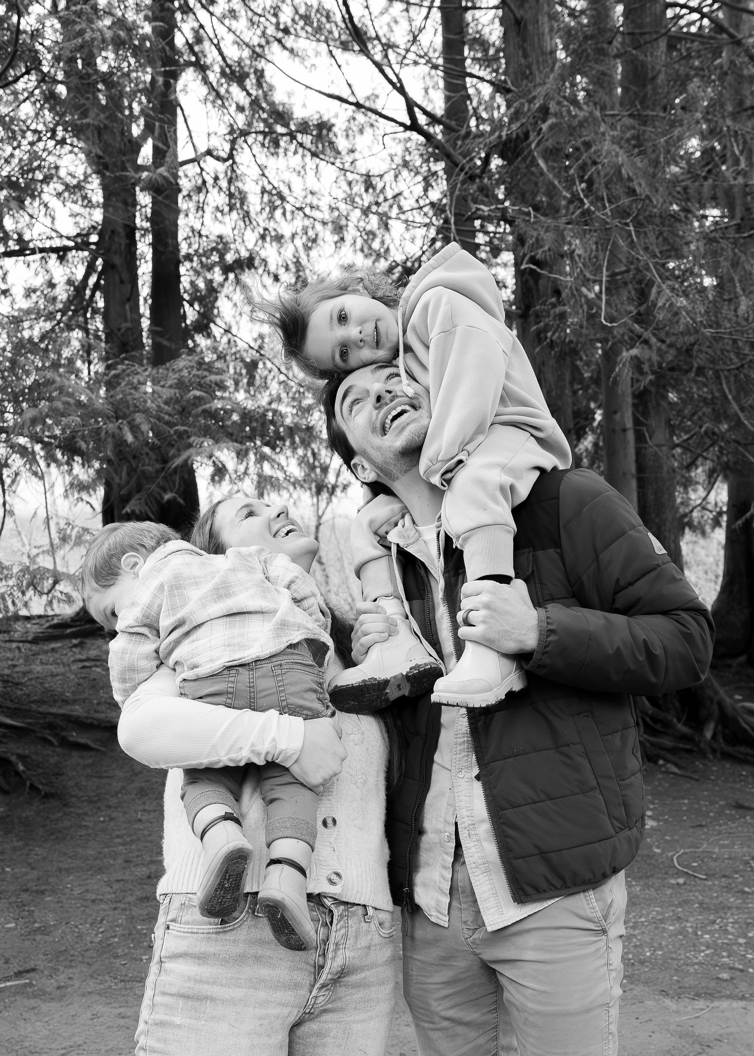 A sequence of black and white photos showing a playful interaction between people in a wooded outdoor setting.