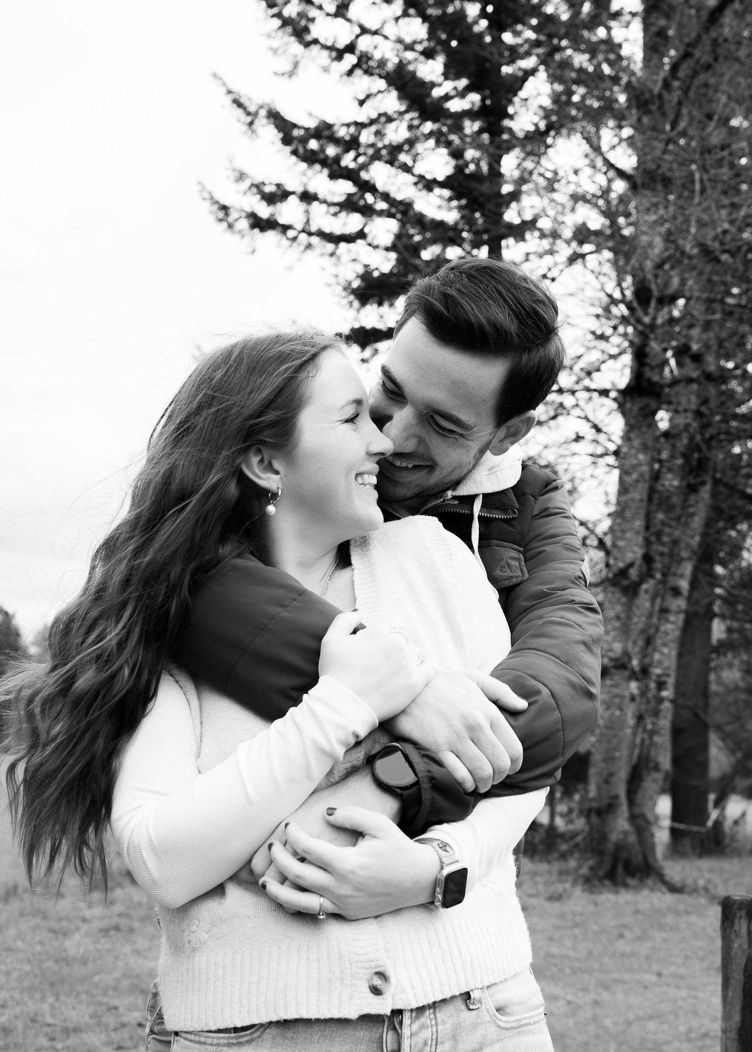 A romantic couple embraces and shares tender moments in a series of black and white photos outdoors among trees.