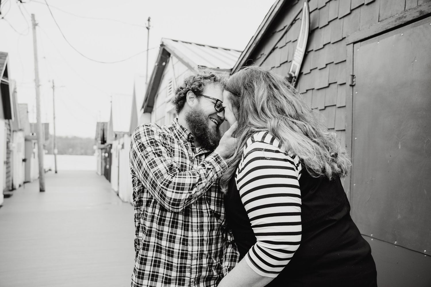 Black and white intimate portrait of two people sharing a tender moment outside a house.