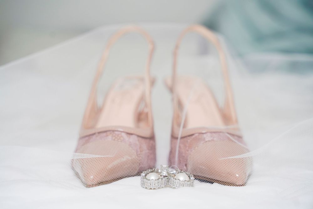 Pink ballet pointe shoes arranged in various positions with elegant wedding rings displayed against a soft white background.