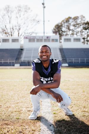 Athletic portraits on football field showing casual poses in sports uniform.