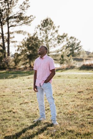 Casual outdoor portraits in a grassy field with pine trees during golden hour.