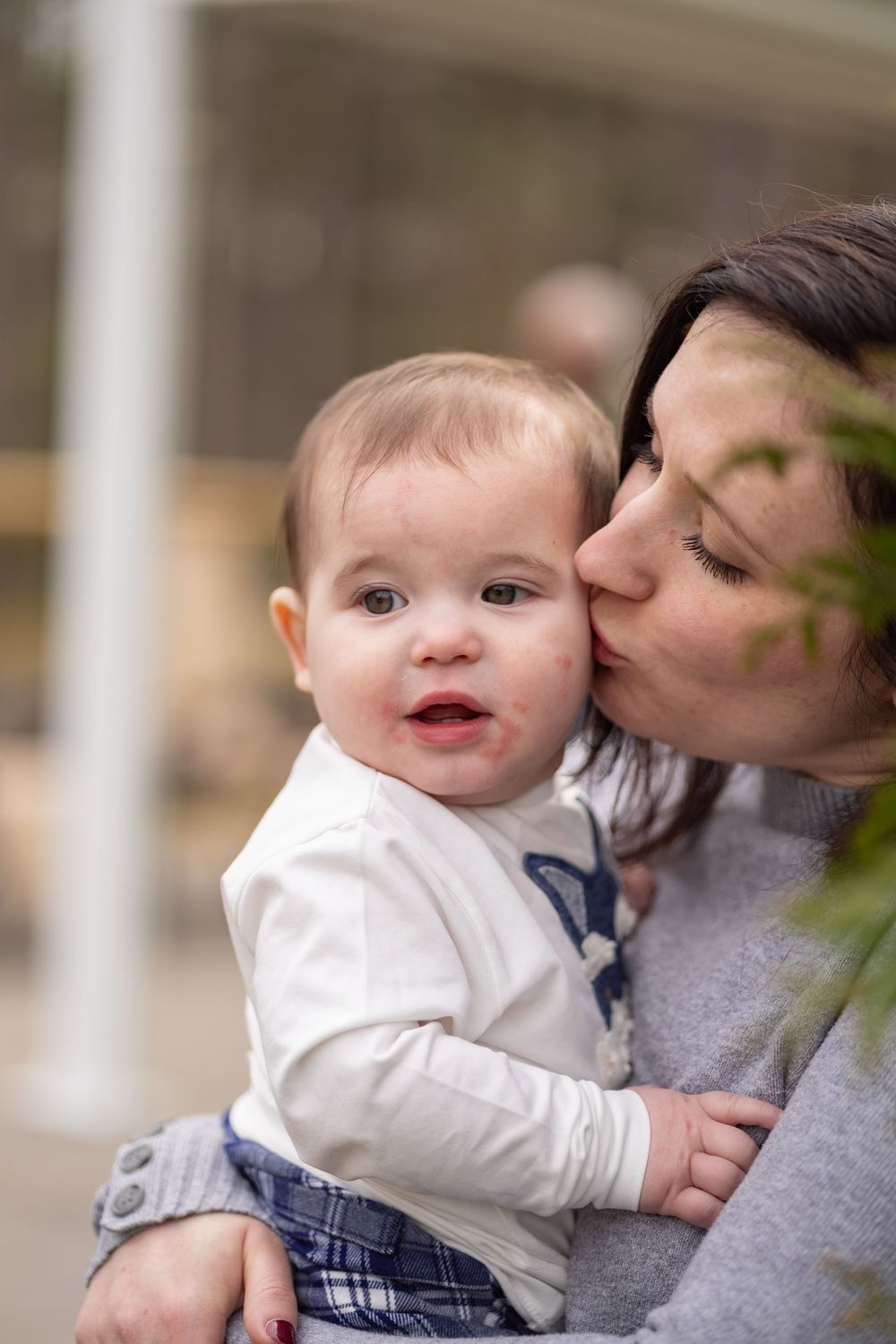 A tender moment between parent and baby in casual attire, sharing a gentle kiss and embrace.