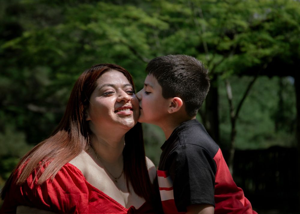 A tender moment shared between two people in a verdant garden setting with red accents.