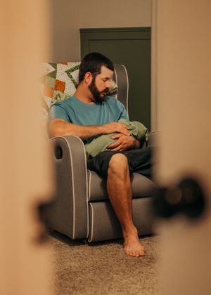 Father holds newborn son in nursery during in home newborn session.
