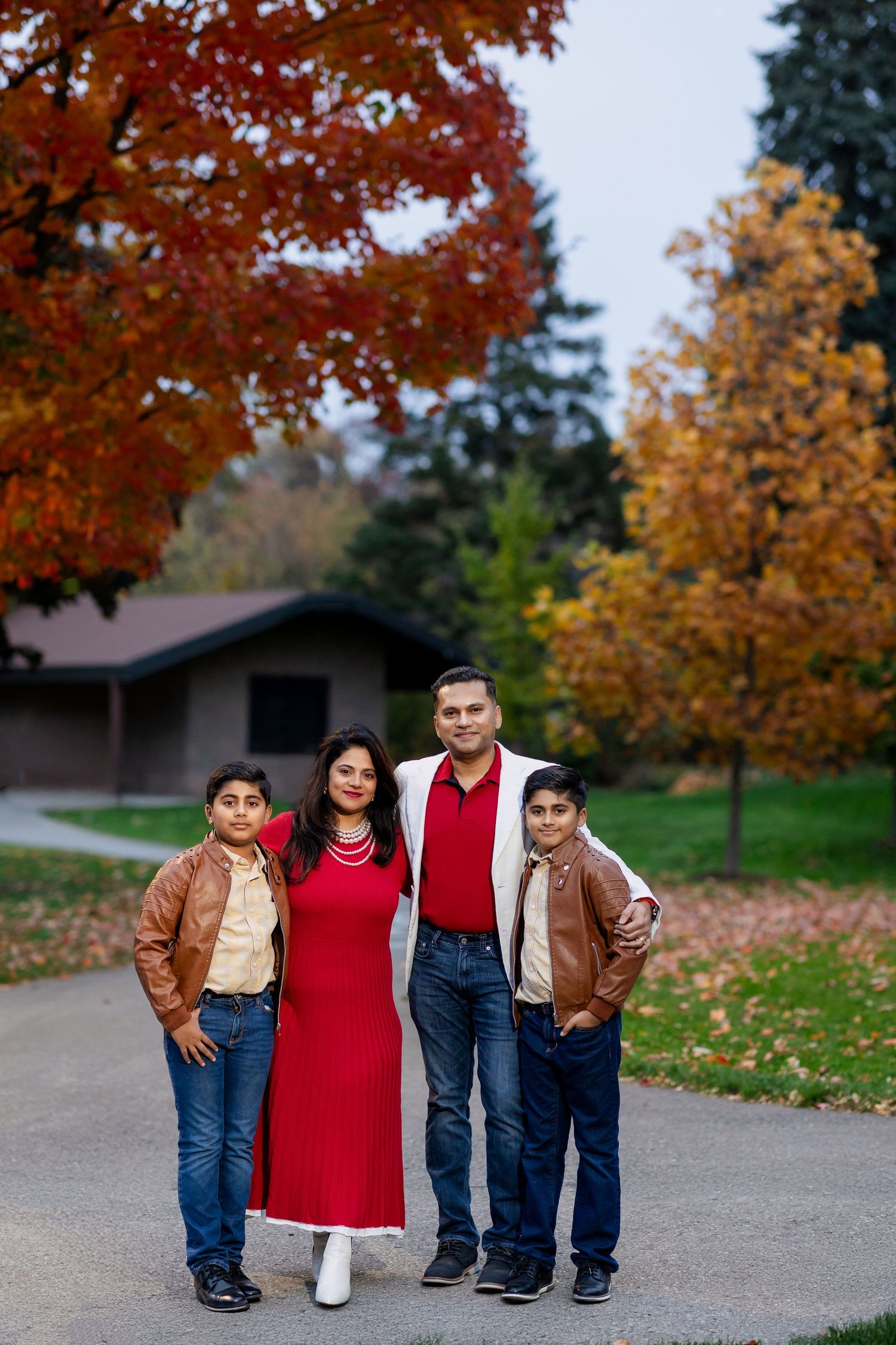 Family portrait session during fall season with vibrant red maple trees in the background.